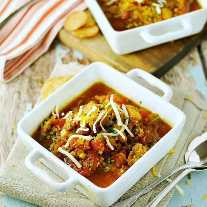 Two small square bowls with orange striped towel and two spoons for pinto bean soup recipe