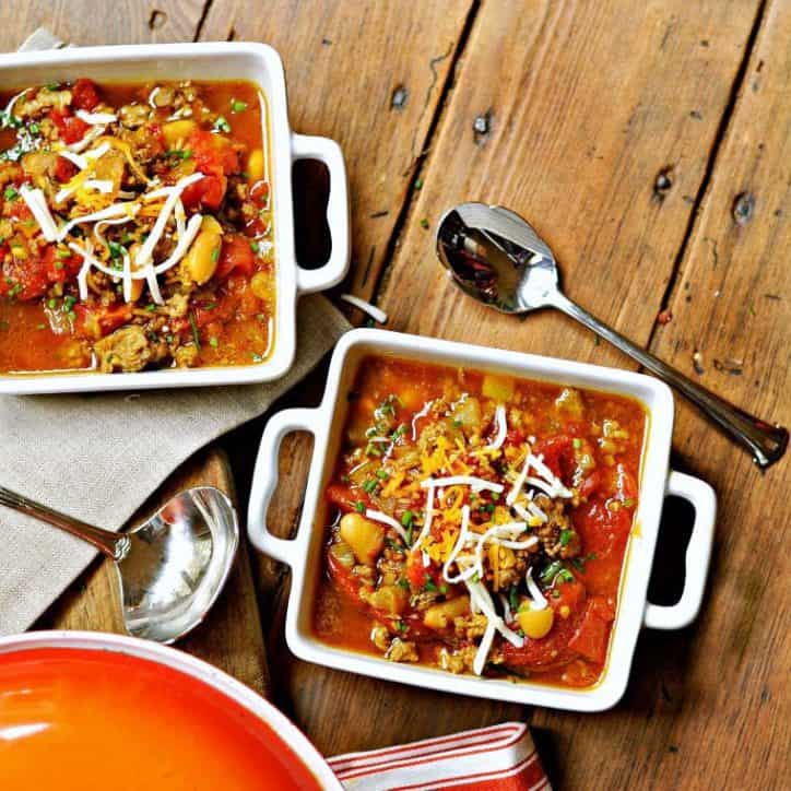 An overhead view of two square bowls of pinto bean soup recipe with a spoon on a wooden background