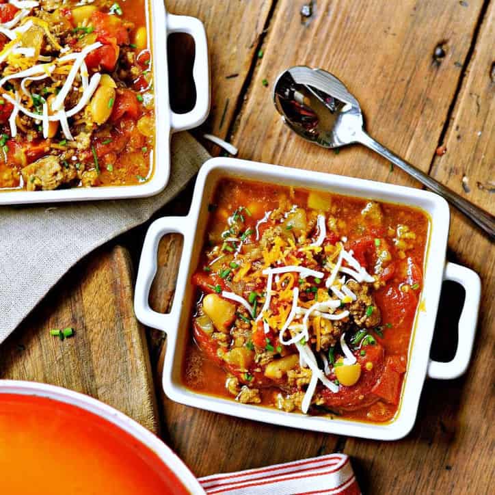 Two square white bowls of pinto bean soup recipe with a spoon