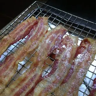 a photo of five strips of cooked bacon on a rack with grease glistening