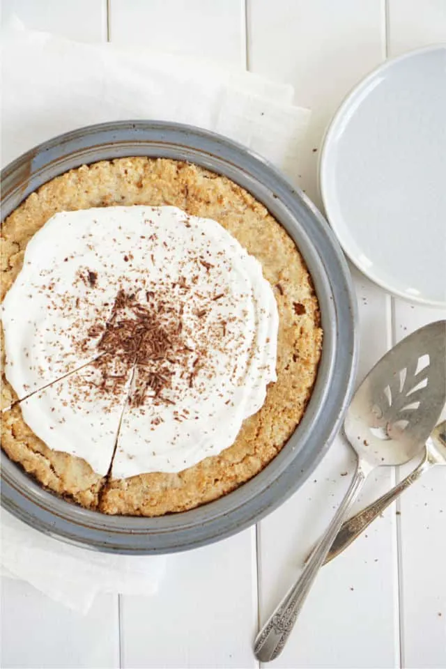 Top down look at the ritz cracker crust of this peanut pie with serving pieces in background