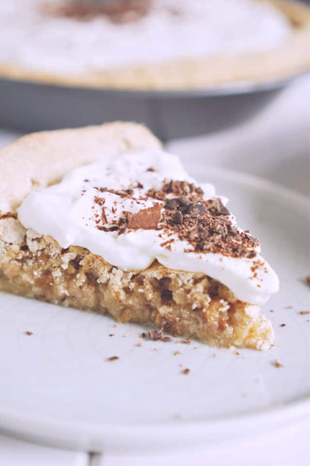 side view of a slice of pie on a white plate with chocolate shavings on top