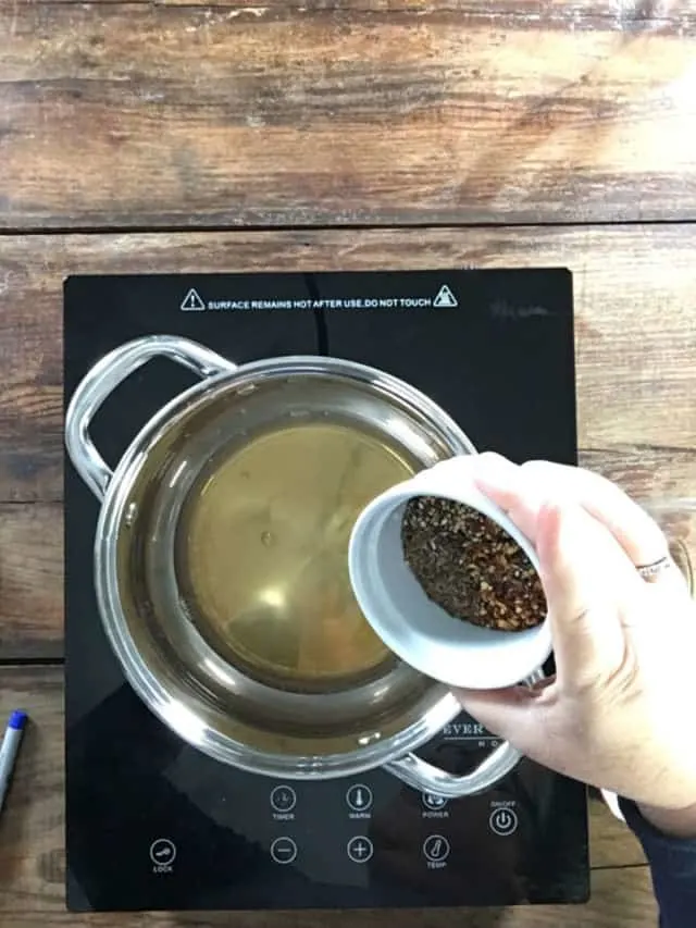 Adding the spices to the saucepan of heated vinegar