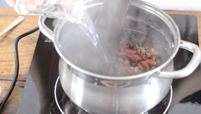 Adding the beans and water to the sauce pan 