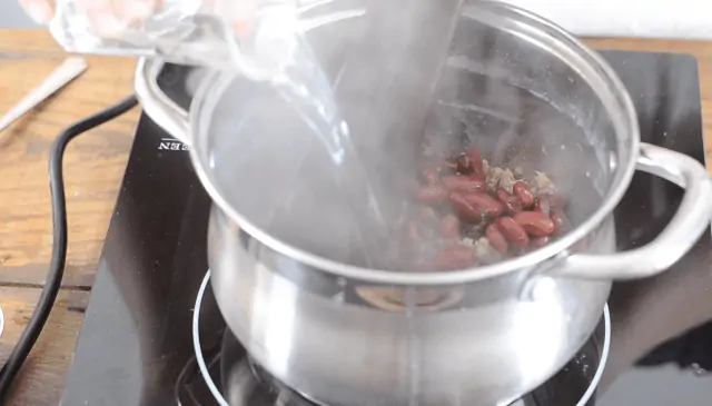 Adding the beans and water to the sauce pan 