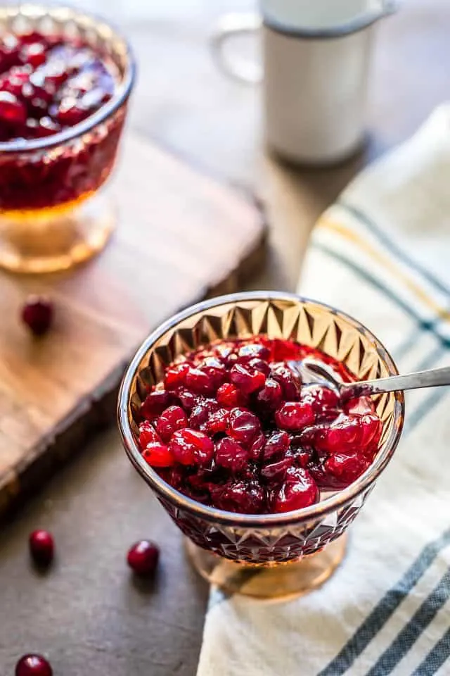 Two goblets of cranberry sauce with applesauce with cutting board and cloth napkin