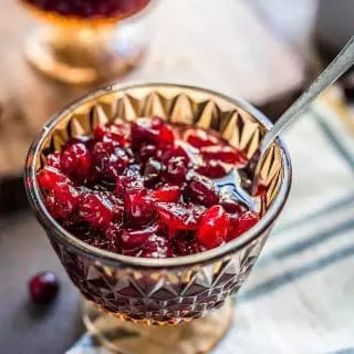 A close up of a crystal goblet with spoon of cranberry sauce with applesauce