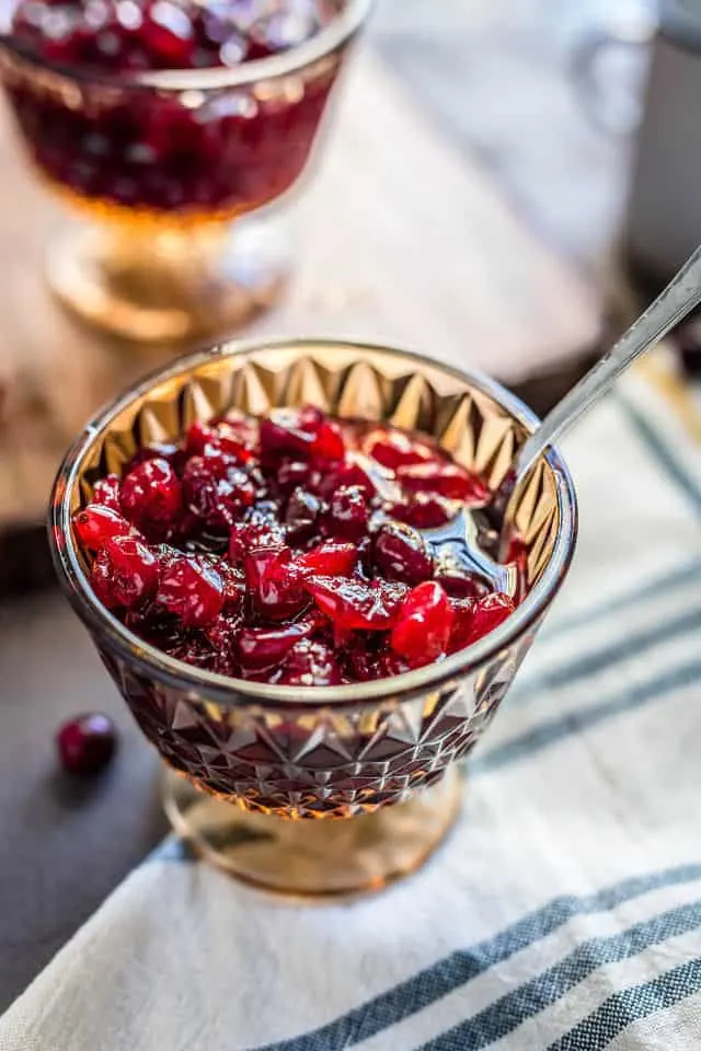 A close up of a crystal goblet with spoon of cranberry sauce with applesauce