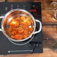 A saucepan full of canned carrots on the stovetop