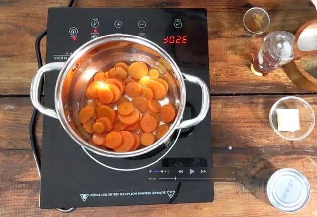 A saucepan full of canned carrots on the stovetop