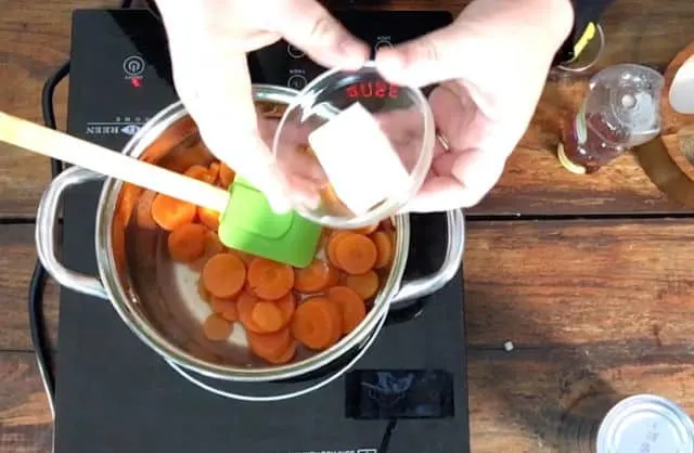 Adding butter to the saucepan of carrots