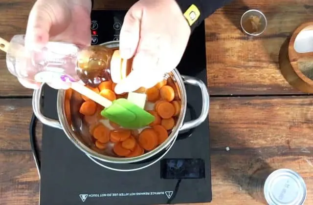 Adding honey to the saucepan of canned carrots