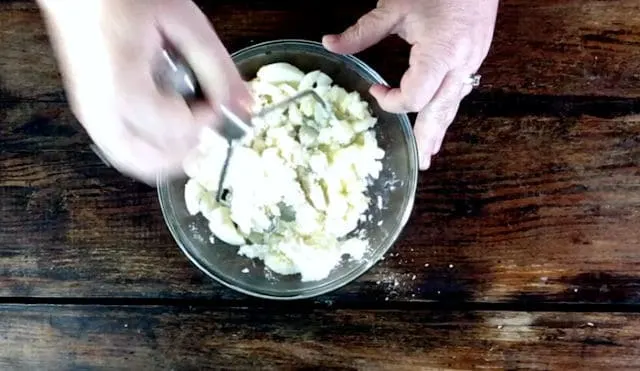Mashing the potatoes with a potatoes masher