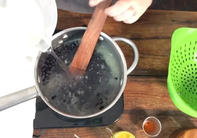 Water being added to the saucepan to cover the beans