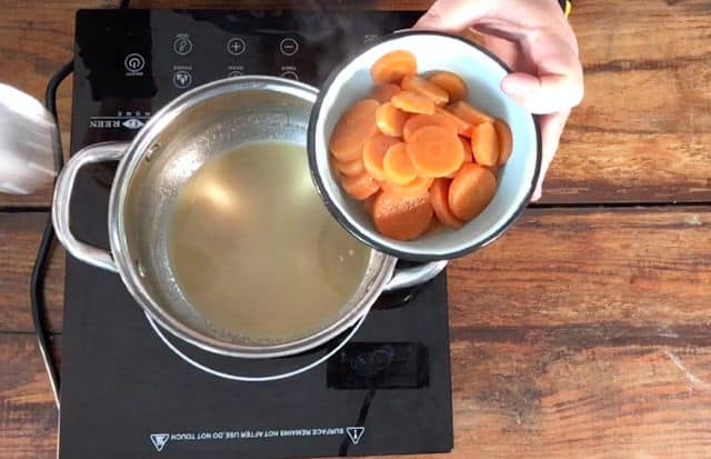 removing the carrots from the saucepan to serving dish