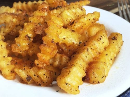 Crispy golden fries on a white plate for how to cook frozen fries