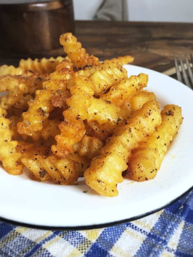 Crispy golden fries on a white plate for how to cook frozen fries