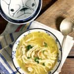 a blue bowl of soup on a white and blue napkin with spoon and extra bowls