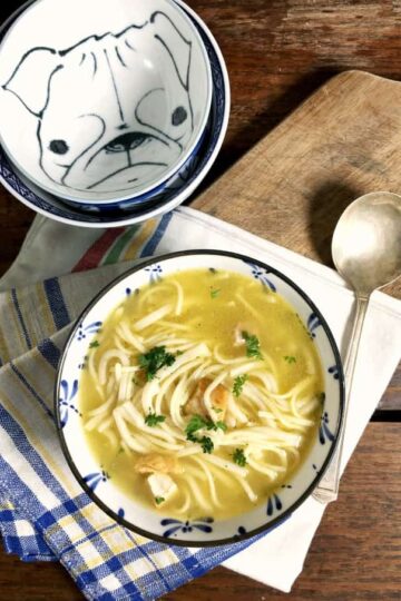 a blue bowl of soup on a white and blue napkin with spoon and extra bowls