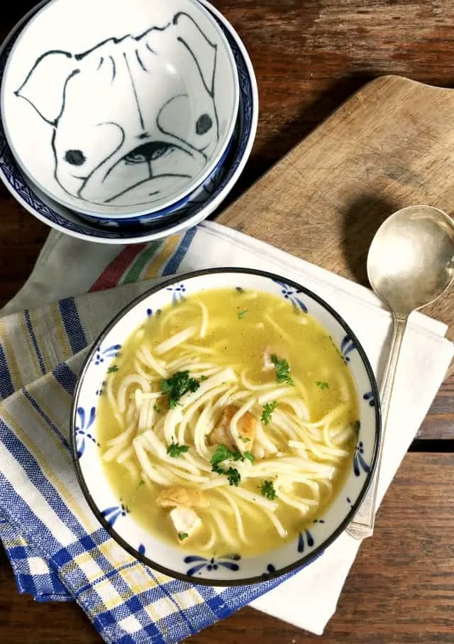 a blue bowl of soup on a white and blue napkin with spoon and extra bowls