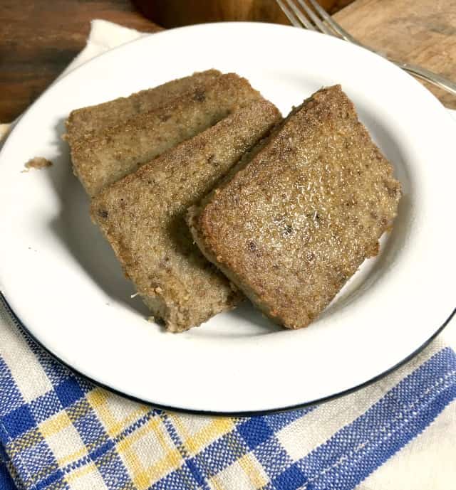 four slices of livermush on white plate with blue, white and yellow napkin