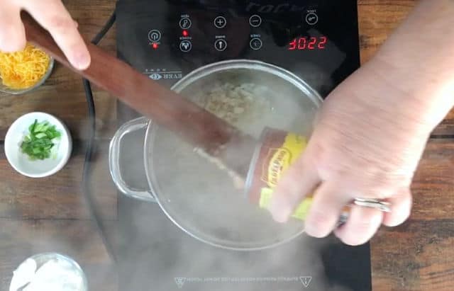 Adding the canned refried beans to the saucepan