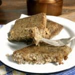 a white plate of scrapple with two slices on the plate and another part slice, fork holding piece