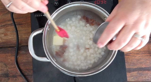 a photo of adding all ingredients to the saucepan for how to cook canned hominy