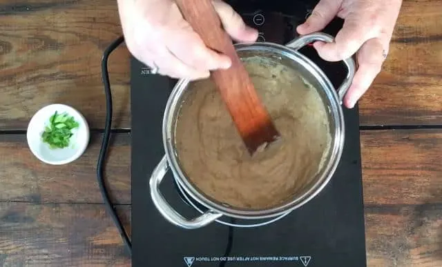 Stirring the finished refried beans in the saucepan