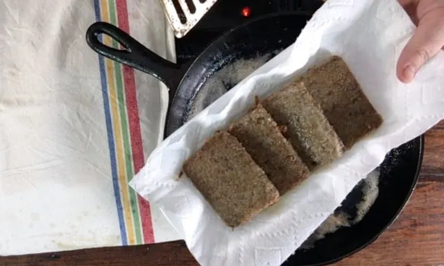 four slices of cooked livermush on a paper towel