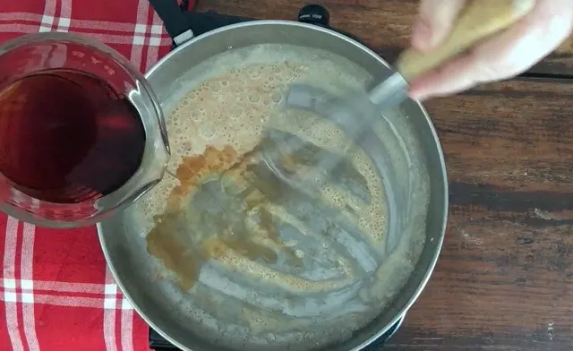 Coffee being poured from a pyrex measure into the frying pan containing the flour and oil