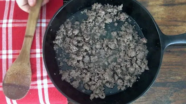 Browned ground beef in pan with gingham napkin