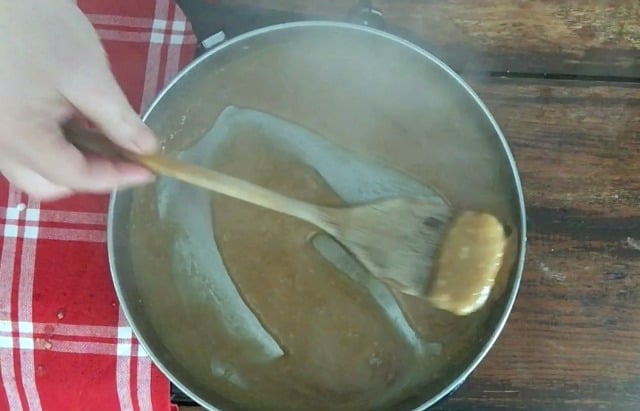 Wooden spoon stirring a frying pan of turkey gravy