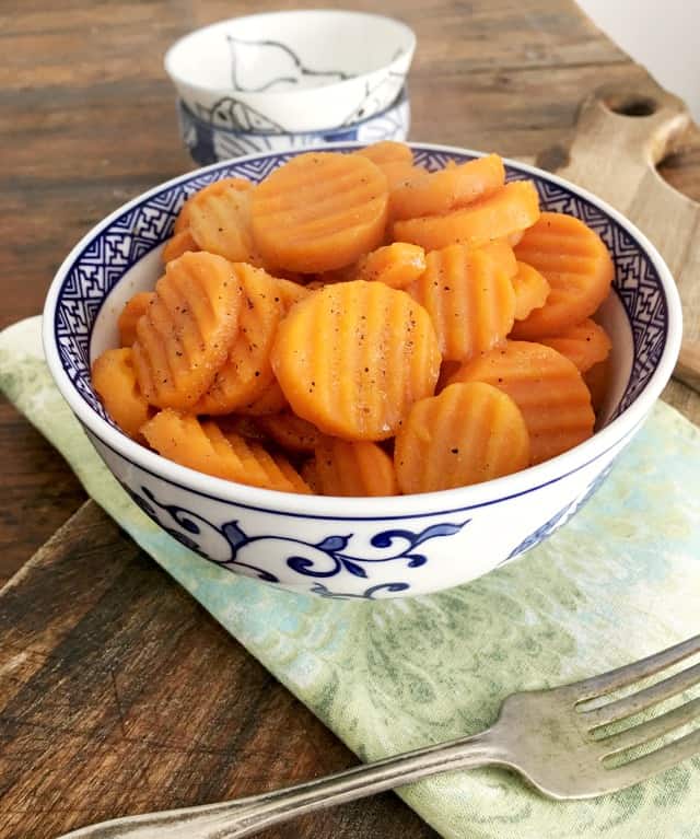 Blue bowl of carrots on green napkin with fork 