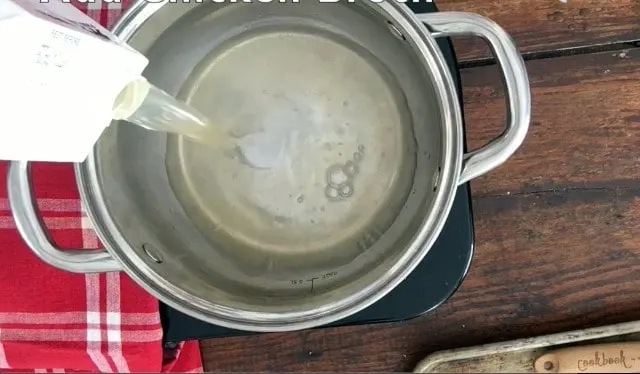 chicken stock being poured into silver pan, red napkin in background