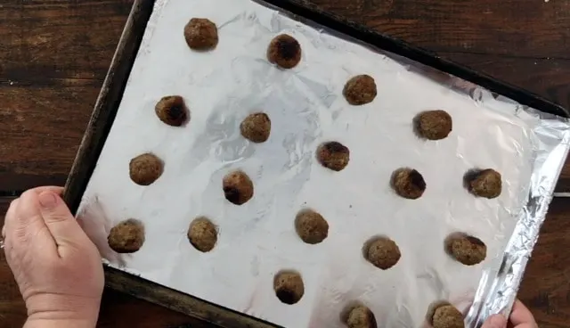 baking sheet with baked meatballs lined up like soldiers