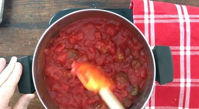 Frozen meatballs being stirred into the sauce