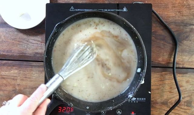 Whisking the brown liquid ingredients in the frying pan to thicken