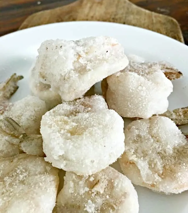 white plate with pile of frozen shrimp on top