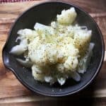 black bowl holding cauliflower on wooden background