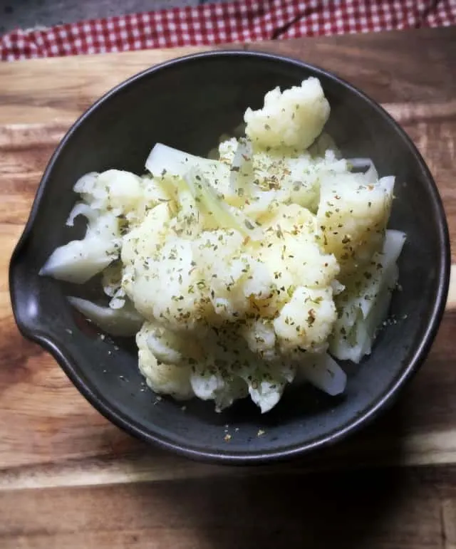 black bowl holding cauliflower on wooden background