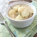 white bowl of stewed potatoes on green napkin with fork