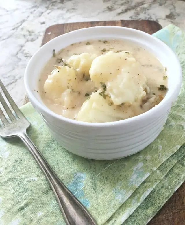 white bowl of stewed potatoes on green napkin with fork