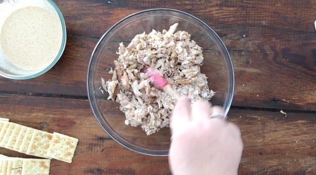 glass bowl of meat with red spatula and hand