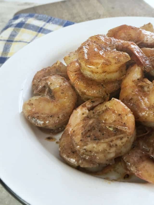 Close up of white plate of bright red pan fried shrimp that were cooked on the stove