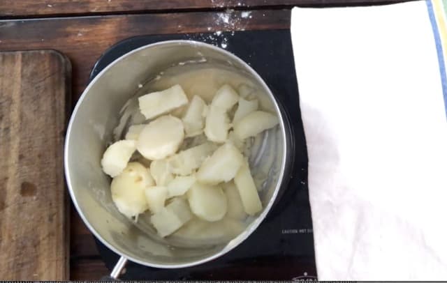 Potatoes and roux in a sauce pan with towel