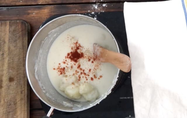 Spices added to the sauce pan of stewed potatoes with towel in background