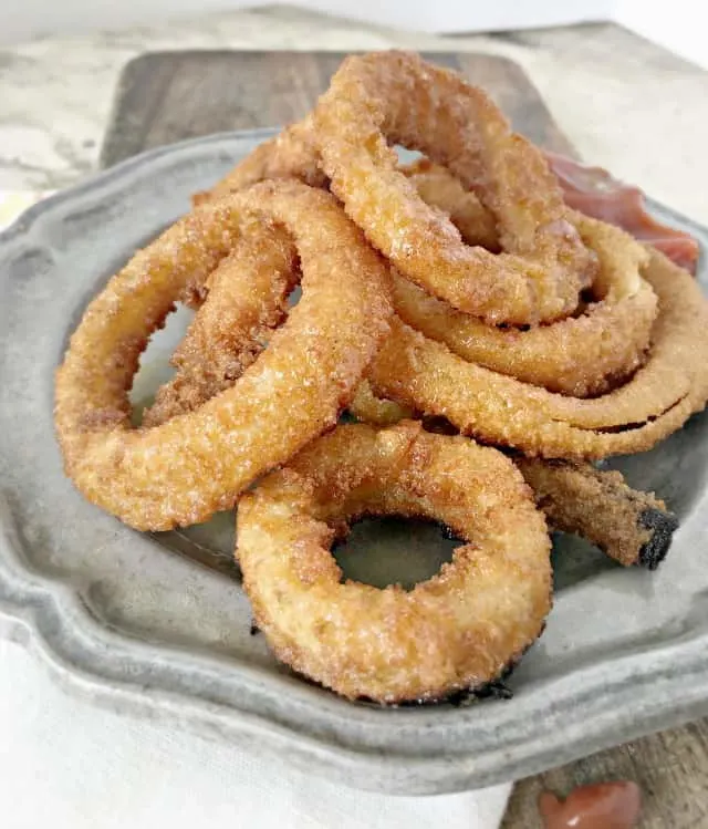 grey plate on a cutting board with crispy onion rings