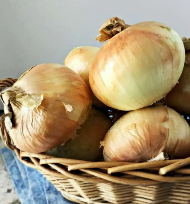 Photo of a basket of onions with blue towel for how to quarter an onion