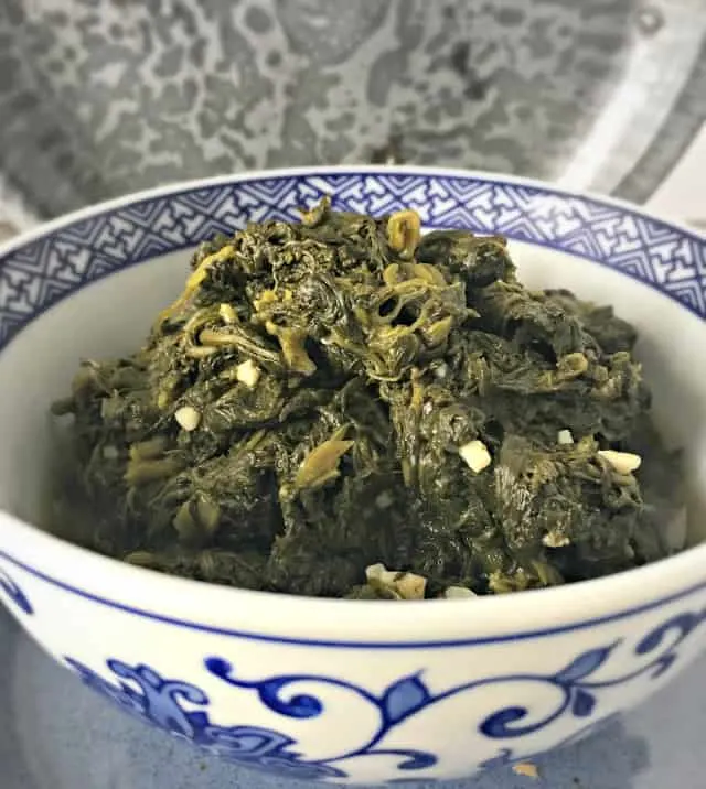 side view of blue and white bowl filled with green spinach